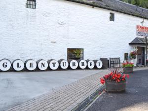 a white building with a bench and flowers in front of it at Tree Tops in Crieff