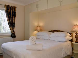 a white bed with a stuffed animal sitting on it at Lodge D- Uk33090 in Dinnet