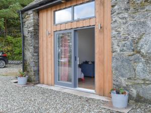 a sliding glass door on a stone building with potted plants at Printmakers Cottage in Bellanoch