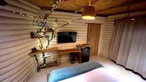 a room with a wall with a tv and a table at Solar Kaeté - Suíte Varandas - Lençóis Maranheses in Santo Amaro