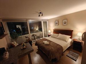 a bedroom with a large bed and a large window at Depto centro de chillan con estacionamiento in Chillán