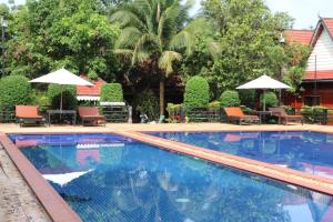 a large swimming pool with chairs and umbrellas at Ratanakiri Phum Khmer resort in Banlung
