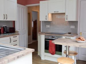 eine Küche mit weißen Schränken und einem Herd mit Backofen in der Unterkunft Hideaway Cottage in Kingsgate + 17 Fotos