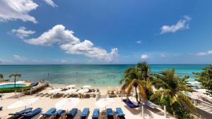 a view of a beach with chairs and the ocean at South Bay Beach Club #16 - 4 Bedroom 4 Bathroom Unit in George Town