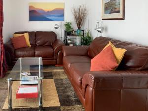 a living room with two brown couches and a glass table at Beach Cottage in Gairloch