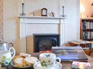 a table with tea cups and biscuits and a fireplace at Upper Ffinnant in Aber-Brân