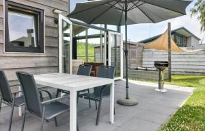 a table and chairs with an umbrella on a patio at 2 Bedroom Cozy Home In Sint-Annaland in Sint Annaland
