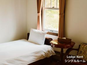 a small bedroom with a bed and a window at Lodge Kent & Cottage Kent in Hokuto