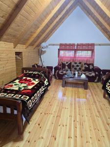 a bedroom with a bed and a couch and wooden floors at Guesthouse Lika in Shkozë