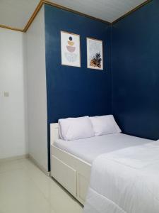 a bedroom with a blue wall and two beds at Gemi Homestay Magelang in Banyurojo