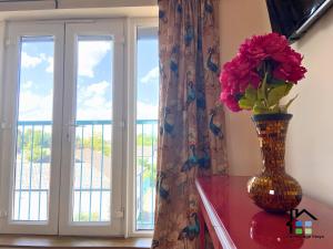 a vase with flowers on a table next to a window at CB Stays - 2 Bedroom & 2 Toilet Flat - Near Mills Road and Train Station with Parking in Cambridge