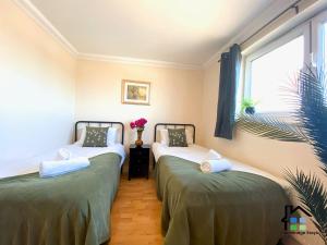 two twin beds in a room with a window at CB Stays - 2 Bedroom & 2 Toilet Flat - Near Mills Road and Train Station with Parking in Cambridge +9 photos