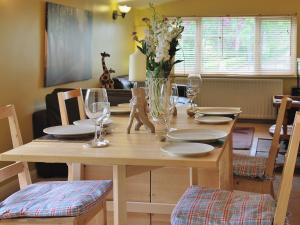 a wooden table with glasses and a vase of flowers at High Moor Cottage in Dufton