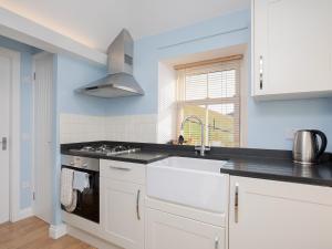 une cuisine blanche avec un évier et une cuisinière dans l'établissement Nettlebush Cottage-Uk5629, à Drummelzier