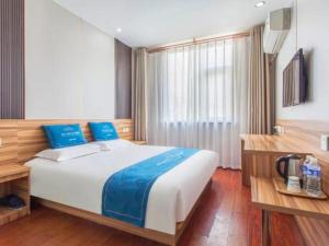 a bedroom with a large bed with blue pillows at PAI Hotel Shijiazhuang Luquan Zoo in Shijiazhuang