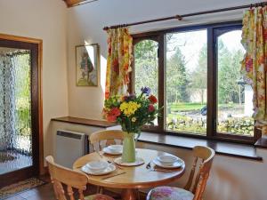 Una mesa de comedor con un jarrón de flores encima. en Forge Mill Cottage, en Dalbeattie