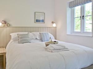 a large white bed in a room with a window at Wishing Well Cottage in Mathon