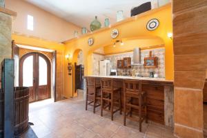 a kitchen with yellow walls and a bar with wooden stools at Cas Mure in Porreres