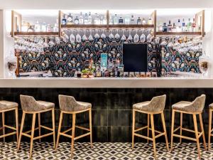 a bar with four stools in front of a counter at Victoria Golf Resort and Spa Managed by Accor in Vilamoura