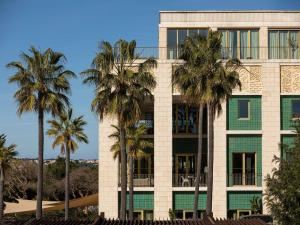 a building with palm trees in front of it at Victoria Golf Resort and Spa Managed by Accor in Vilamoura