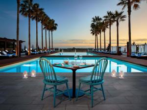 a table and chairs next to a pool with palm trees at Victoria Golf Resort and Spa Managed by Accor in Vilamoura