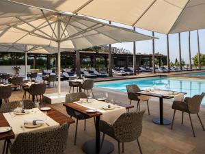 a restaurant with tables and umbrellas next to a pool at Victoria Golf Resort and Spa Managed by Accor in Vilamoura