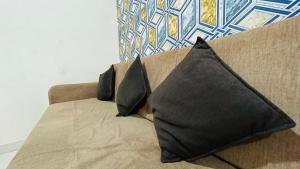 a brown couch with two black pillows on it at Studio flats in Candolim in Candolim +1 photo