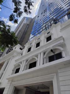 a white house with a tall building in the background at BGC Uptown Park Suites Tower 1 - 2 Bedroom and 2 Bath Condo in Manila