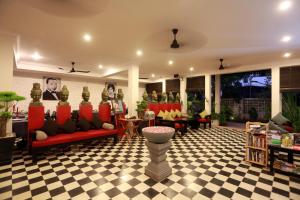 Khmer Mansion Boutique Hotel في سيام ريب: غرفة معيشة مع كنب احمر وارضية مضلمة