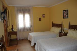 1 dormitorio con 2 camas y ventana en Hostal Casa Perico en Larraga
