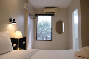 a bedroom with a bed and a window with a palm tree at The Loom Rangsit in Ban Lam Phak Kut