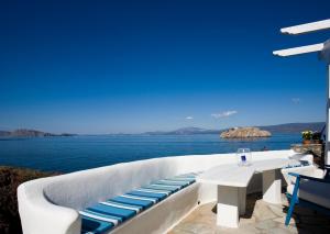 un patio blanco con mesa y vistas al océano en Villa Ostria en Vlikhós