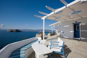 a patio with white tables and chairs and the water at Villa Ostria in Vlikhós