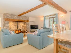 a living room with two blue couches and a fireplace at Mulberry Cottage in North Wootton