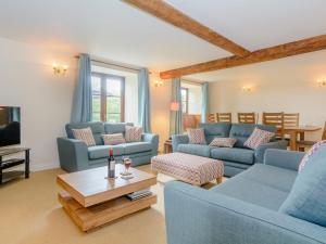 a living room with blue couches and a coffee table at Mulberry Cottage in North Wootton