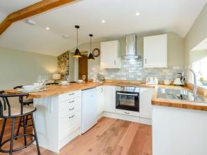 a kitchen with white cabinets and wooden floors at Stackyard Cottage in Felmingham