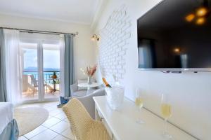 a living room with a television on a white wall at Delfino Blu Wellness Boutique Hotel in Agios Stefanos