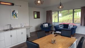 a kitchen and living room with a table and chairs at Little Forest Cabins No 3 in Feilding