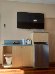 a kitchen with a refrigerator and a tv on the wall at The Original Bel-Air Motel in Port Macquarie
