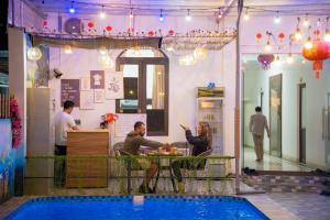 宁平Puppy Hotel Homestay的一群人坐在桌旁的游泳池旁 更多31张照片