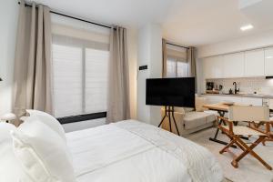 a bedroom with a white bed and a kitchen at Arena One Studio in Fuengirola