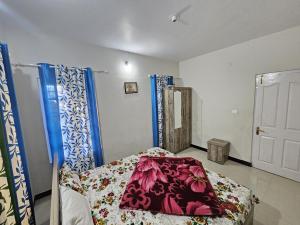 a bedroom with a bed with a blanket on it at Sait's Westhill View Resort in Ooty