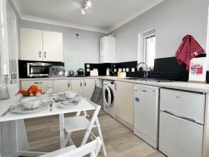 una cucina con armadi bianchi e un tavolo con frutta di Jayne Cottage a Tarbert