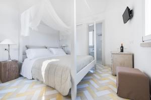 ファヴィニャーナにあるフィリアート ホスピタリティ カラモーニ ディ ファヴィニャーナ アパートメンツの白いベッドルーム(大きな白いベッド1台、椅子付)