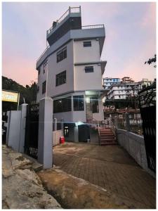 a tall white building with a lot of windows at Hotel Miravin Bed and Breakfast Shillong Near Jackson Trace Road - Crinoline Falls - Free Parking and Free Wi-Fi Facilities - Best Hotel In Shilong in Shillong