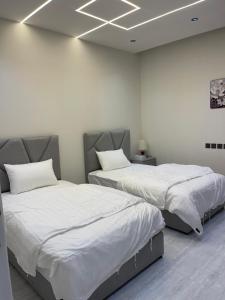 two beds in a room with white walls at شقق في الحمرا هاي رايز in Al Khobar