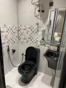a bathroom with a black toilet and a sink at شقق في الحمرا هاي رايز in Al Khobar