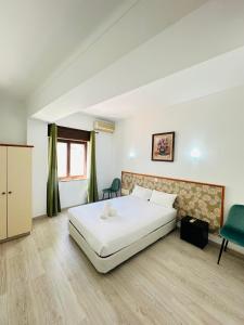 a bedroom with a white bed and a green chair at Residencial Pimenta ,Portimao,Algarve in Portimão
