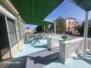 a porch with a green umbrella and a table and chairs at Happy House in Lixouri