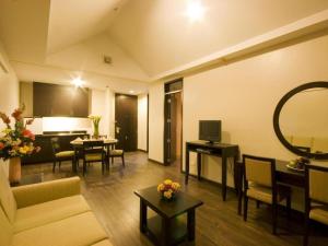 a living room with a couch and tables and a television at Baguio Burnham Suites Hotel in Baguio